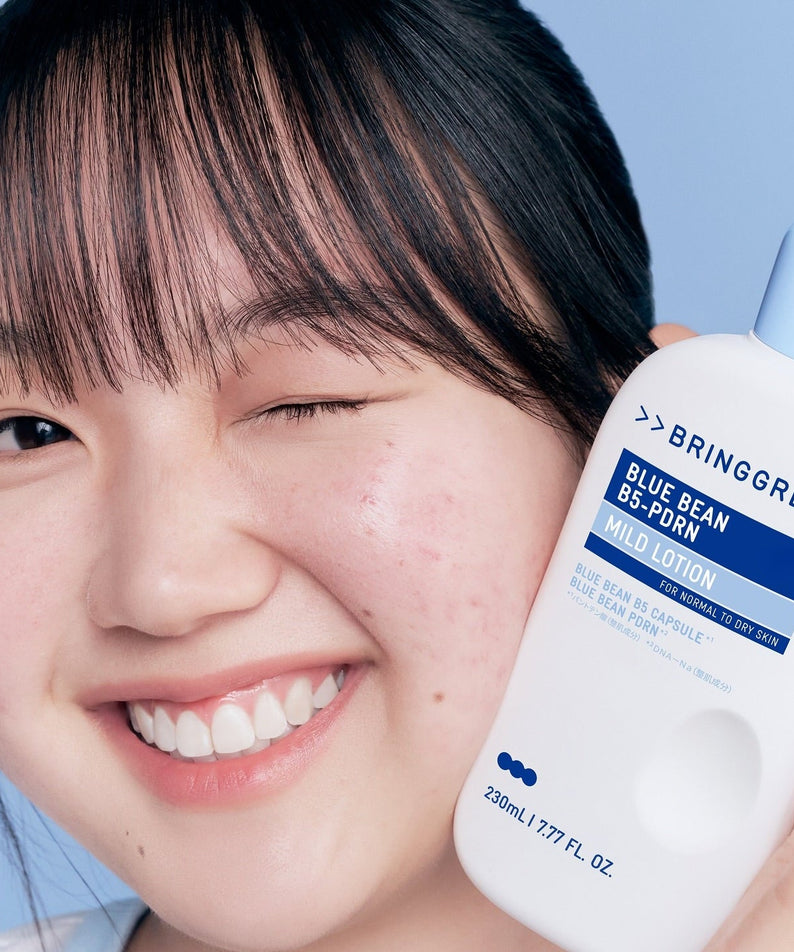 Person holding BRINGGREEN Blue Bean B5-PDRN Mild Lotion 230ml bottle with eyes closed and smiling