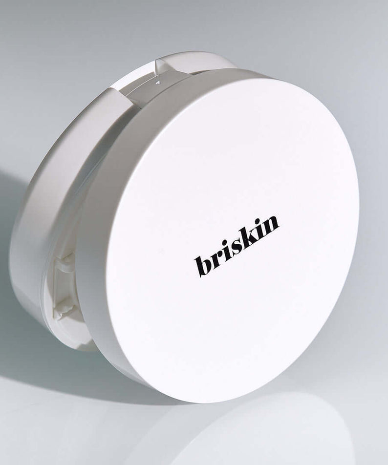 BRISKIN Exo-Glow Secondskin Cushion 15g product photo featuring a sleek white compact with the brand logo on a light background.