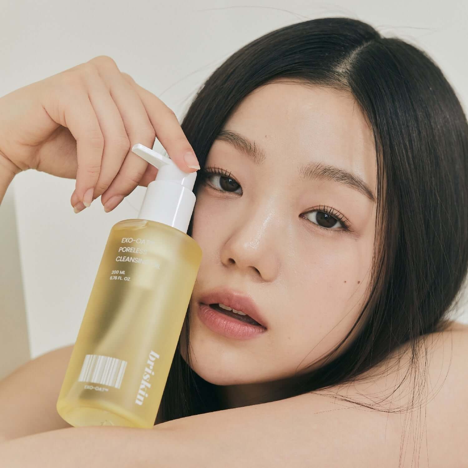 Woman holding BRISKIN Exo-Oat Poreless Cleansing Oil 200ml bottle
