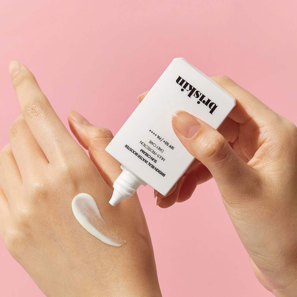 BRISKIN Real Water Booster Sun Cream SPF+PA++++ 50ml being applied to hand against pink background