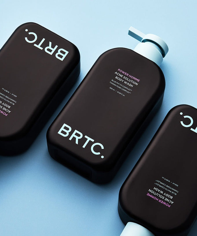 Three bottles of BRTC Power Homme Acne Solution Body Wash 500ml arranged on a light blue background.
