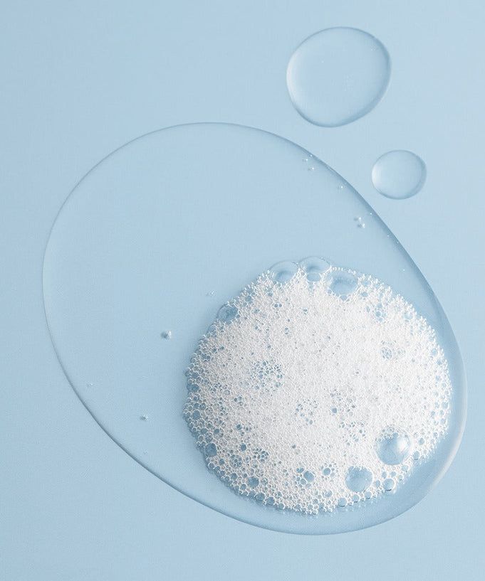 Texture of BRTC Power Homme Acne Solution Body Wash 500ml with bubbles on blue background