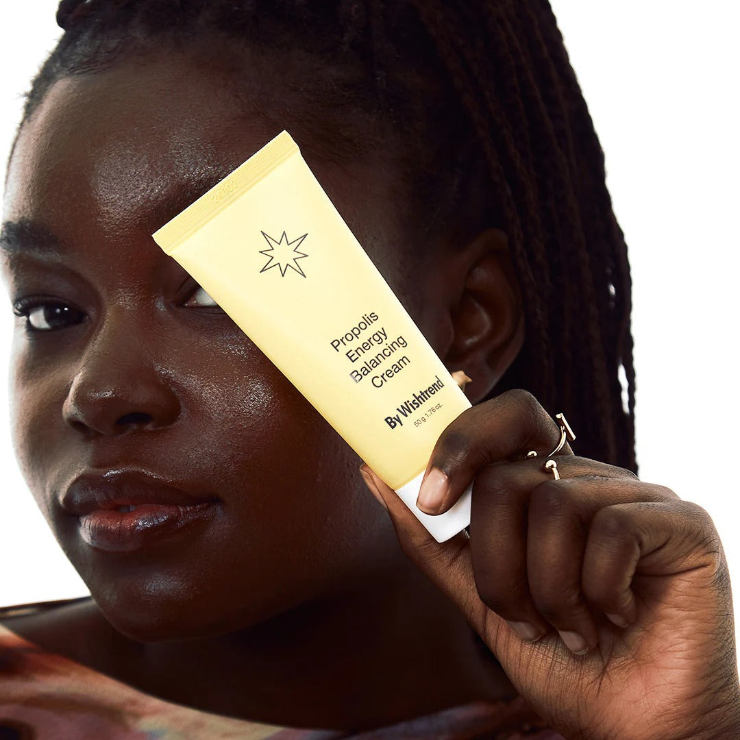 Person holding BY WISHTREND Propolis Energy Balancing Cream 50g tube showcasing skincare product packaging.