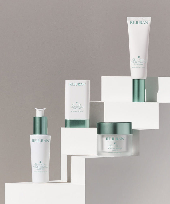 REJURAN Biome Healer Touth Formula Sunscreen 50ml displayed with skincare products on geometric stands