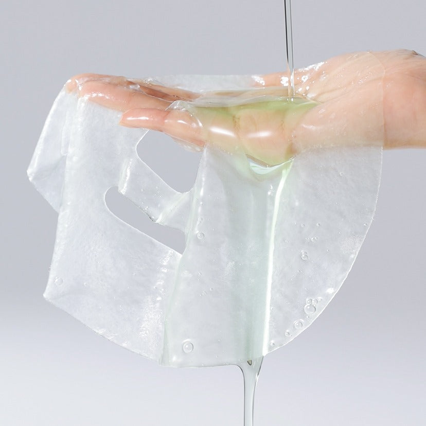 Close-up of a CELIMAX Cica Serum Mask sheet being held, highlighting texture and serum.
