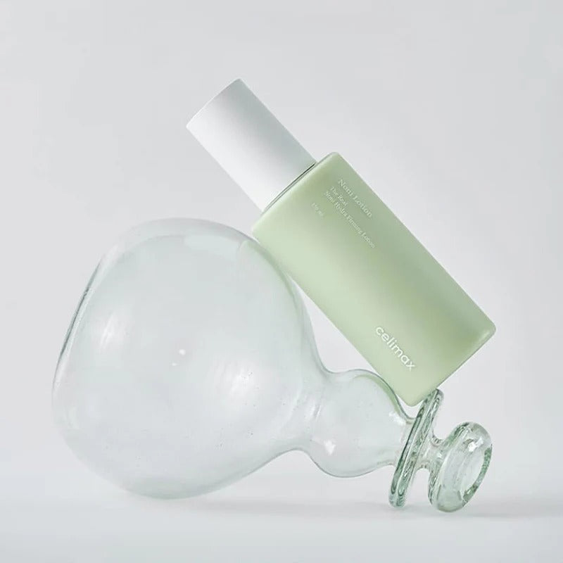 CELIMAX The Real Nino Hydra Firming Lotion 150ml bottle leaning against a glass object on a white background