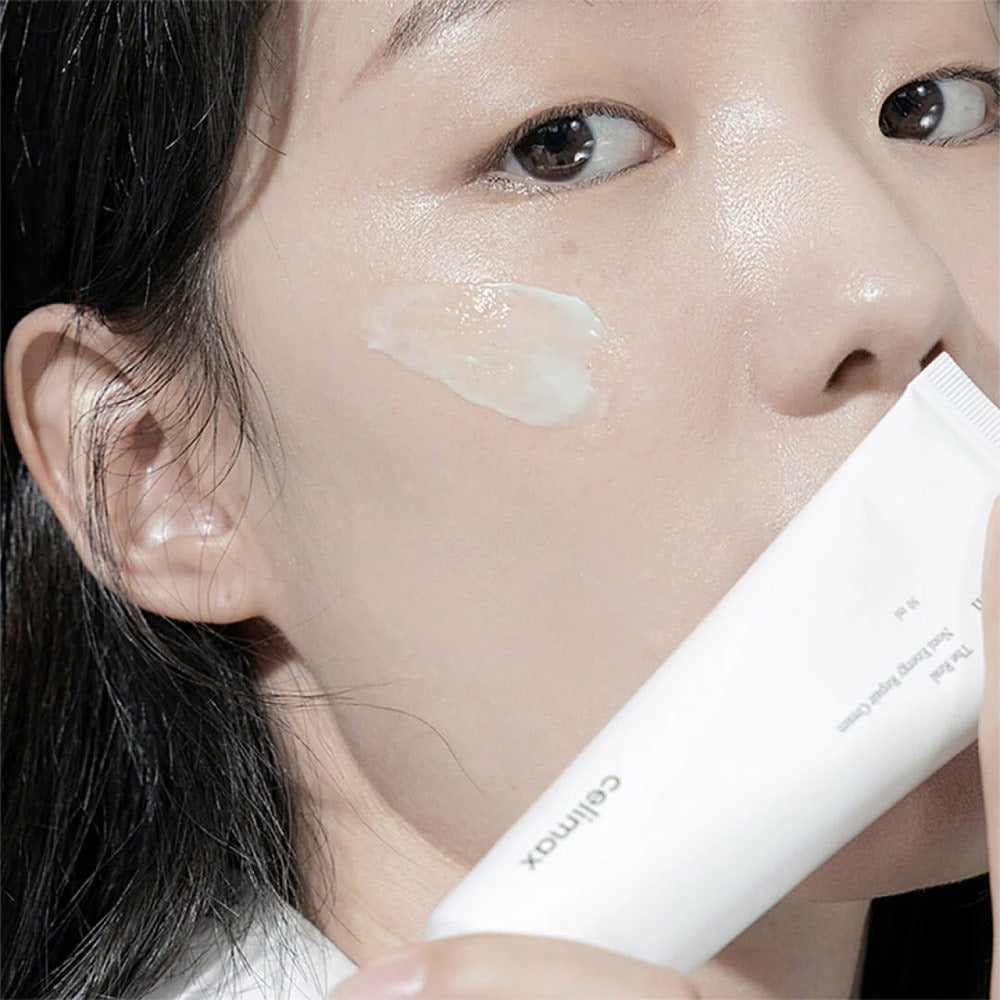 Woman applying CELIMAX The Real Noni Energy Repair Cream 50ml to her face.