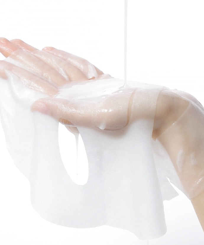 A hand holding a CELIMAX Brightening Pore Blemish Serum Mask sheet with serum dripping, showcasing hydrating and clarifying properties.