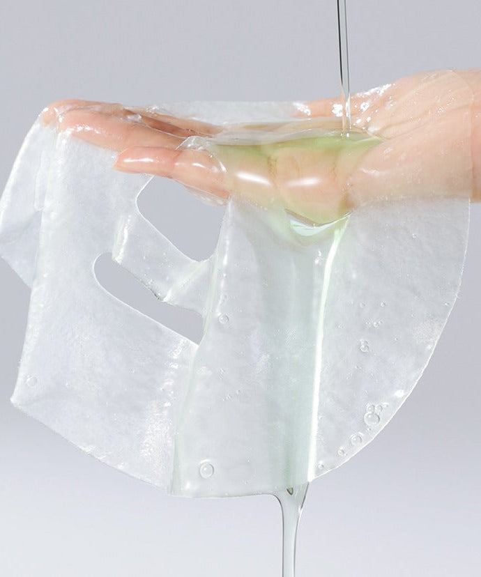 Close-up of a CELIMAX Cica Serum Mask sheet being held, highlighting texture and serum.