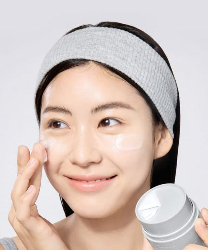 Woman applying CELIMAX Dual Barrier Purifying Cleansing Balm 50ml to her face for skincare routine.