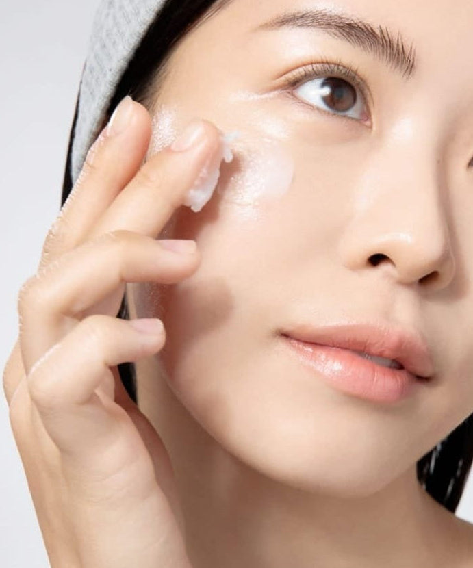 Woman applying skin care product on face