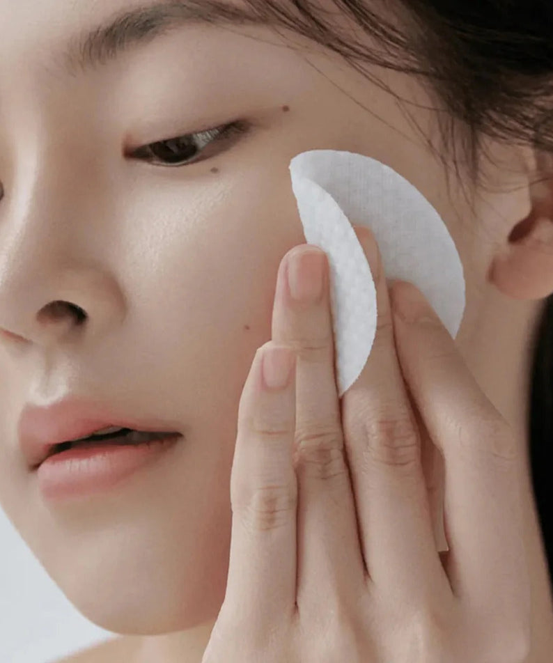 Woman using CELIMAX Ji Woo Gae Heartleaf BHA Peeling Pad 60 Pads on face, showcasing product effectiveness and gentle exfoliation.