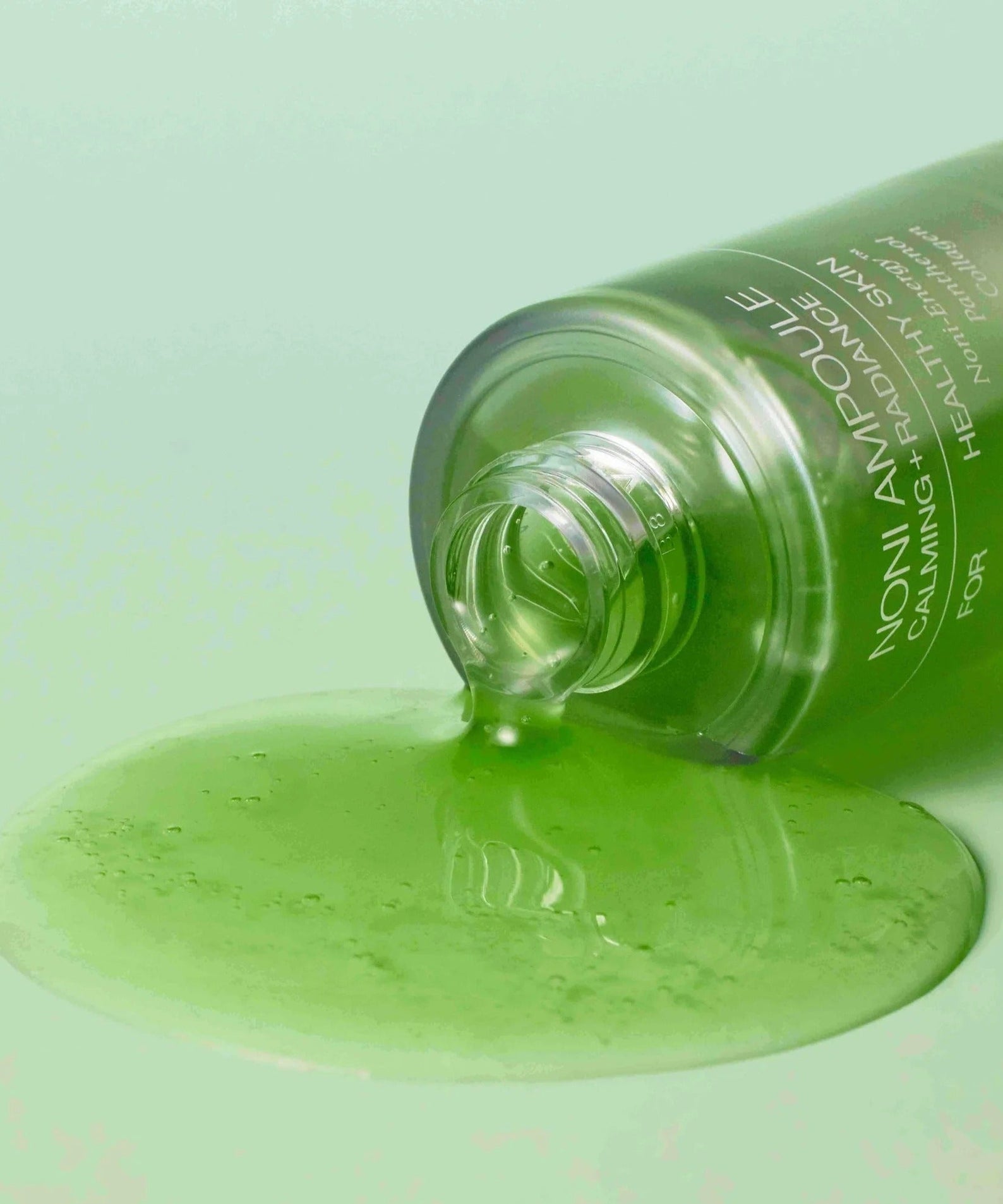 CELIMAX Noni Ampoule Calming+Radiance 100ml spilled on green surface showcasing texture and color