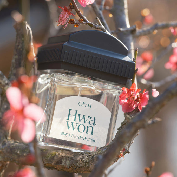 CHWI (CHI) Hwa Won Parfume 50ml bottle among blooming flowers.