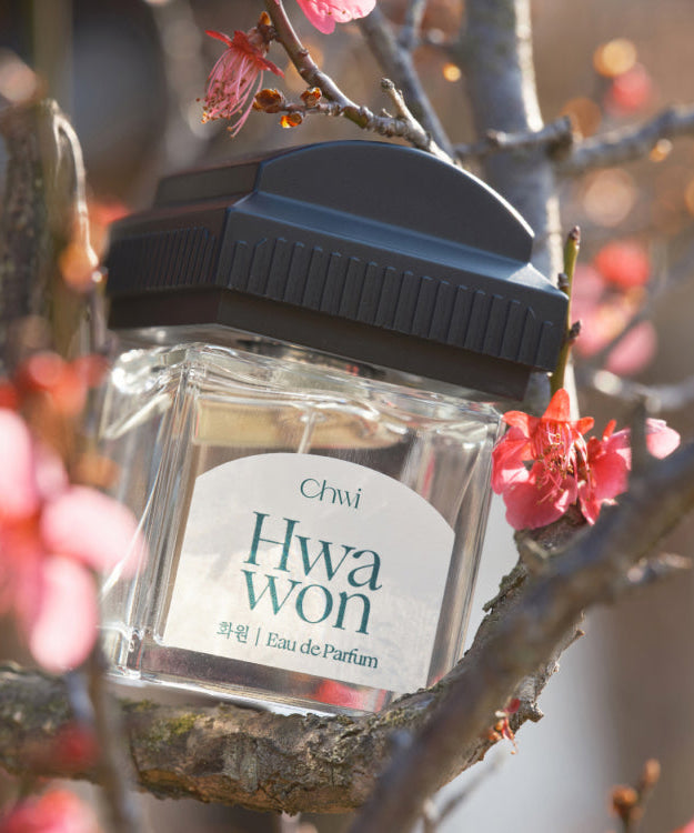 CHWI (CHI) Hwa Won Parfume 50ml bottle among blooming flowers.