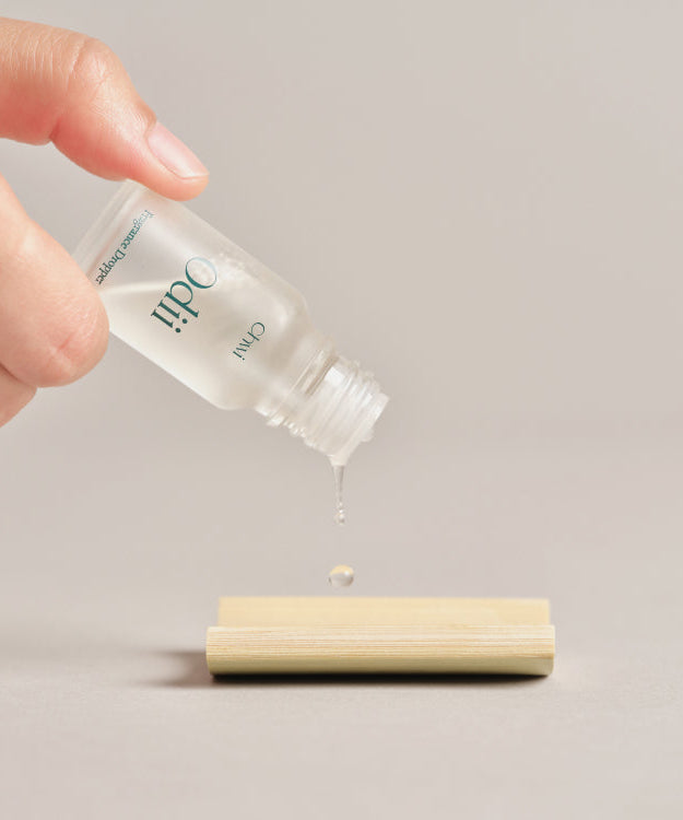 Hand using CHWI (CHI) Odii Frangrance Dropper 10ml to apply fragrance on surface.