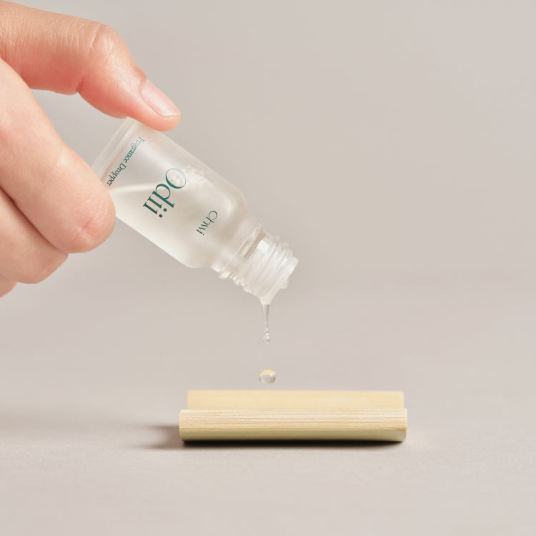 Hand using CHWI (CHI) Odii Frangrance Dropper 10ml to apply fragrance on surface.