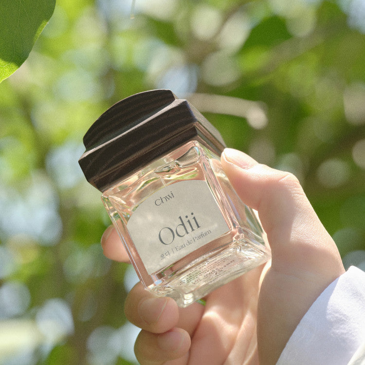 Person holding a bottle of CHWI (CHI) Odii Parfume 50ml with a natural background