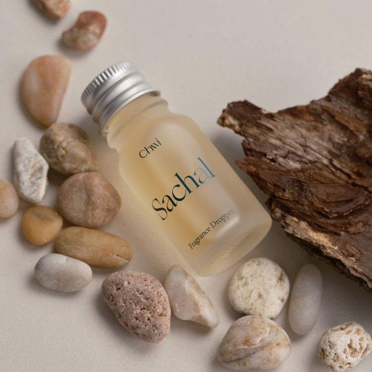 CHWI (CHI) Sachak Fraangrance Dropper 10ml surrounded by natural stones and driftwood on a neutral background.