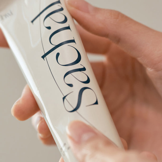 Close-up of a hand holding CHWI (CHI) Sachal Hand Cream 50ml tube, showcasing the elegant packaging design.