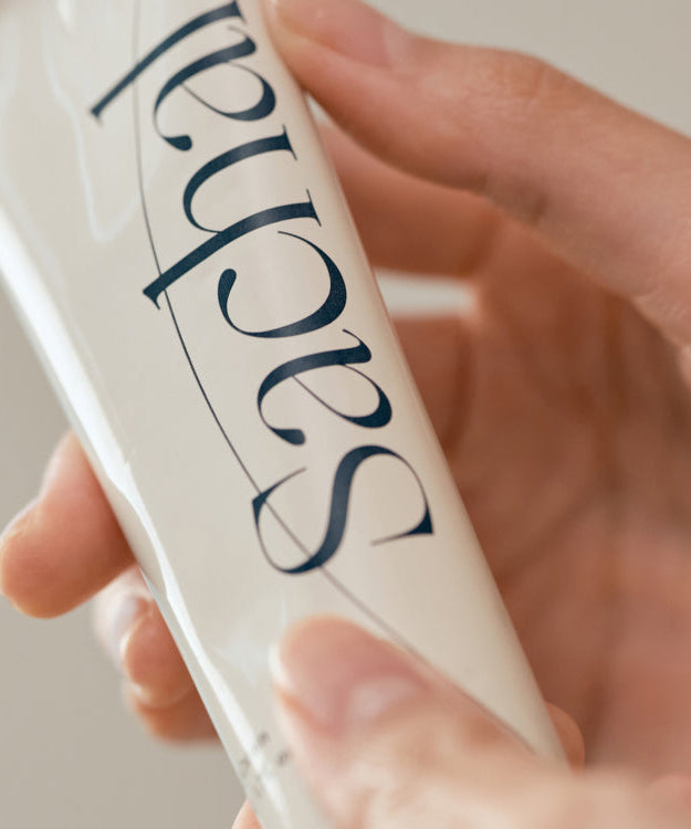 Close-up of a hand holding CHWI (CHI) Sachal Hand Cream 50ml tube, showcasing the elegant packaging design.
