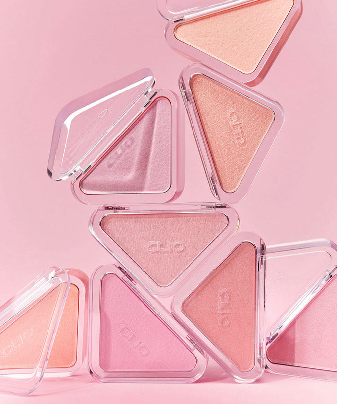 A collection of CLIO Essential Blush Tab products in various pink shades against a pink background, showcasing their elegant design.