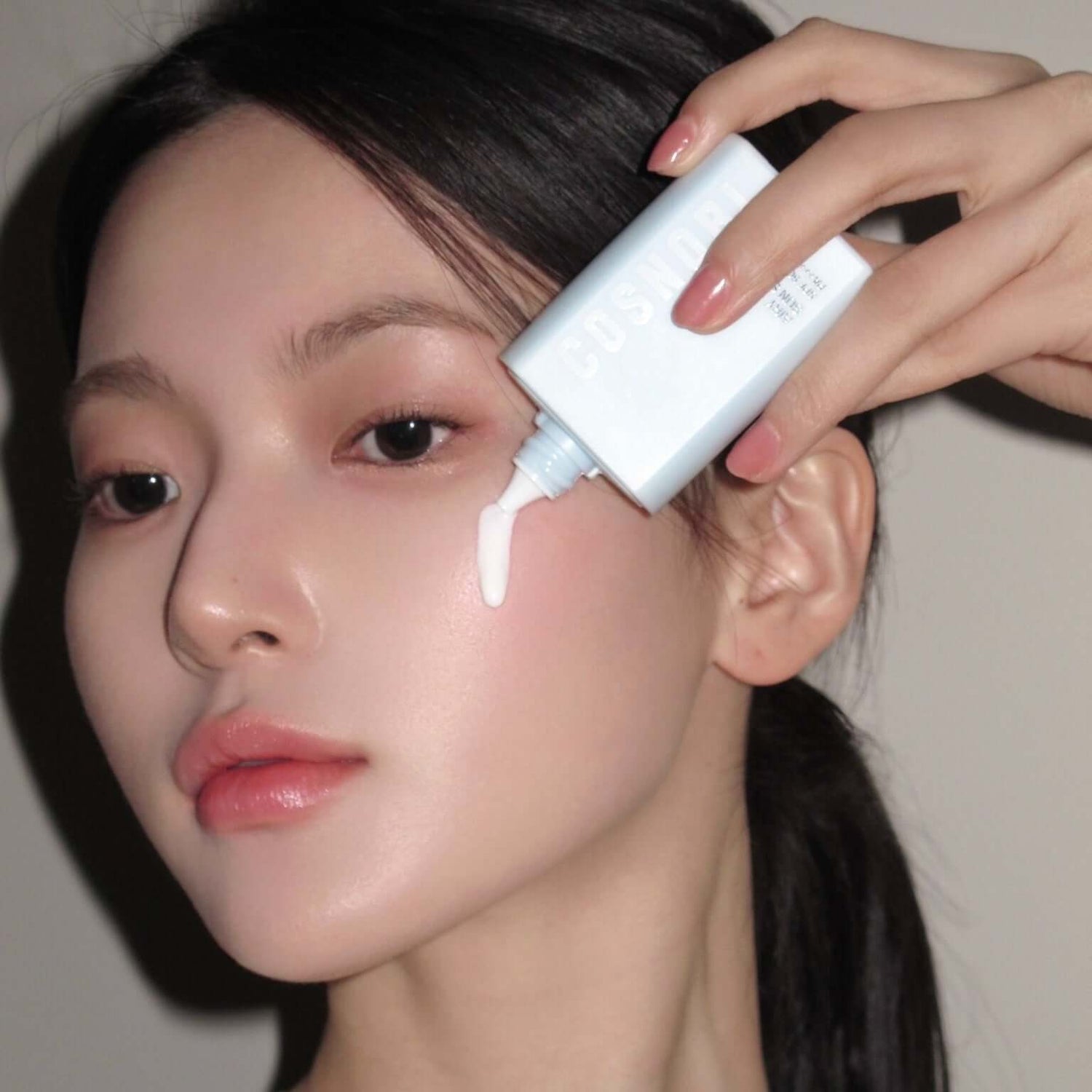 Woman applying COSNORI Airy Tone Up Sun Serum on her face for skincare
