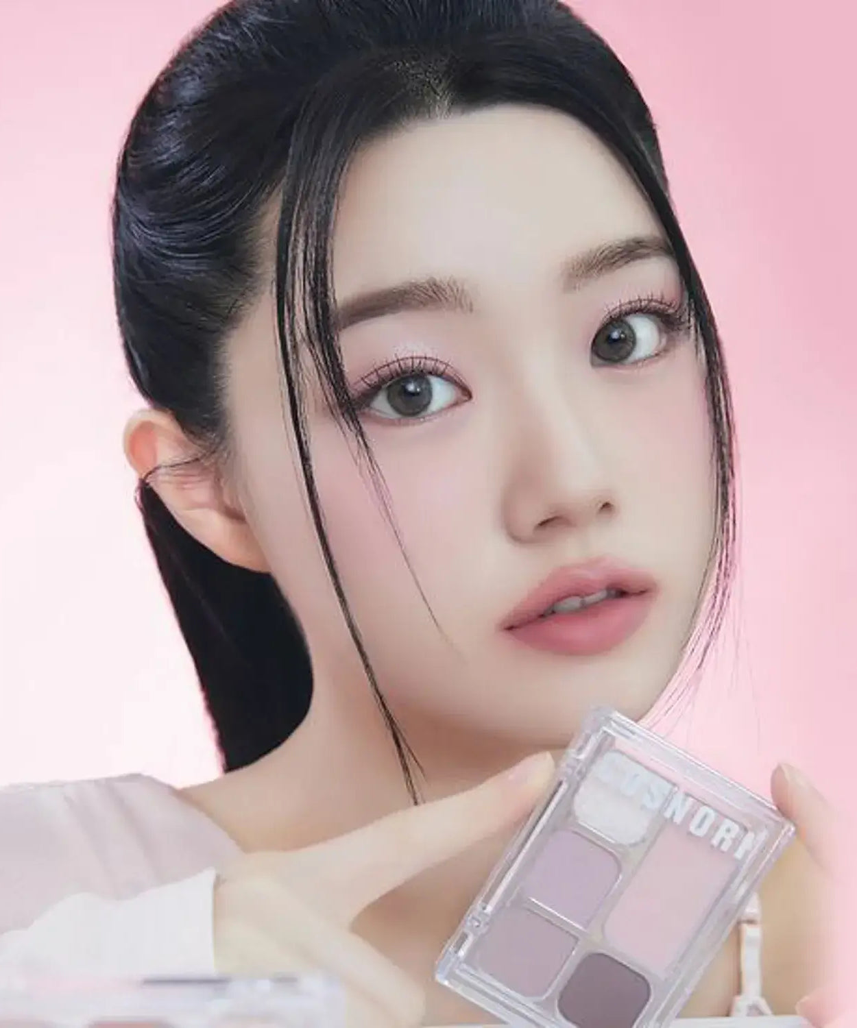 Woman showcasing COSNORI My Moment Eye Palette with a soft pink background.