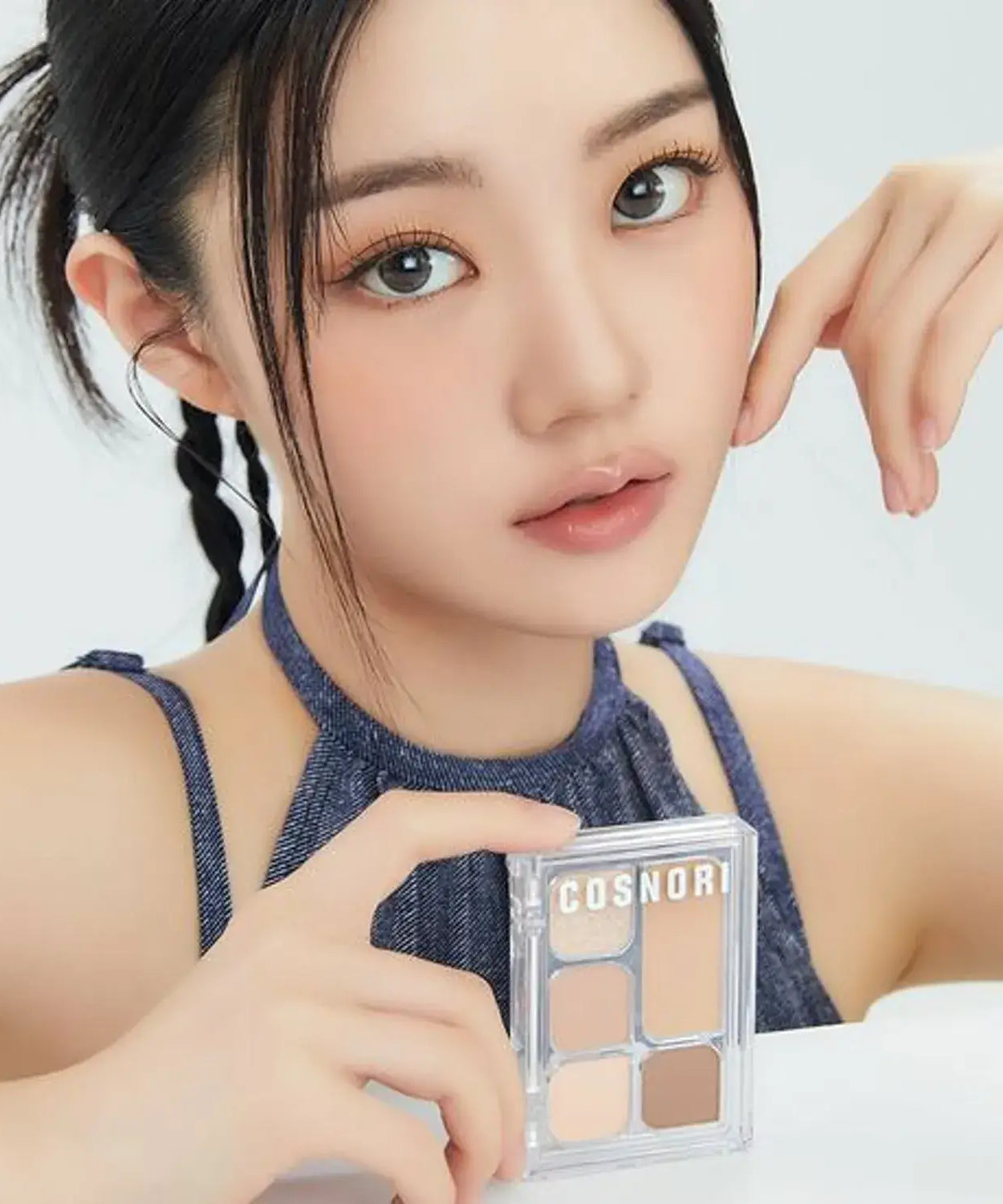 Woman holding COSNORI My Moment Eye Palette in hand, showcasing its shades for makeup application.