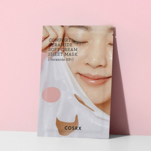Packaging of COSRX Balancium Comfort Ceramide Soft Cream Sheet Mask against a pink background.