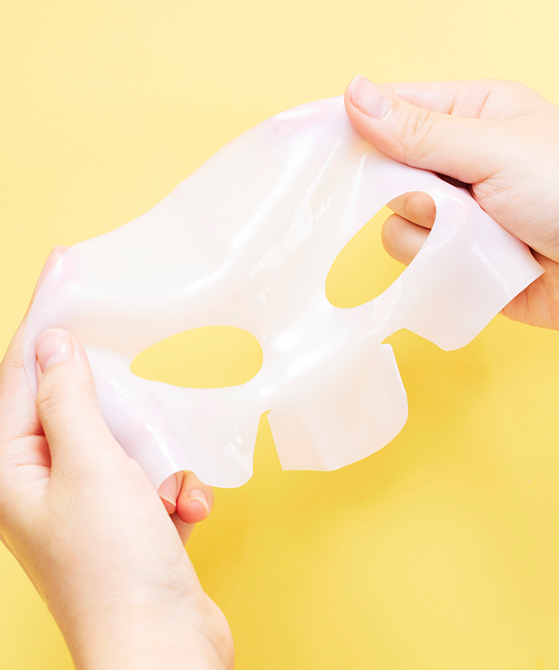 Hands holding COSRX Advanced Snail Mucin Glass Glow Hydrogel Mask (3 mask) against a yellow background.