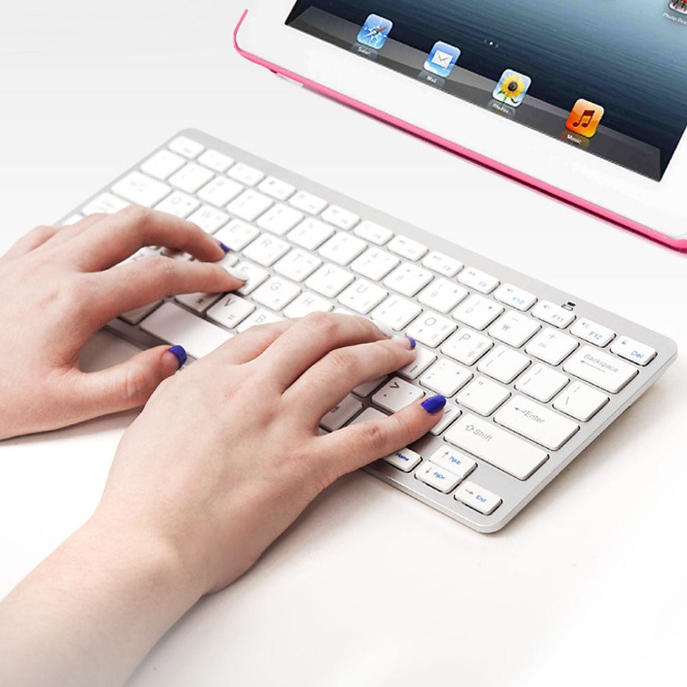 Hands typing on COSY Basic Silver Bluetooth Keyboard connected to a tablet, highlighting sleek design and wireless functionality.