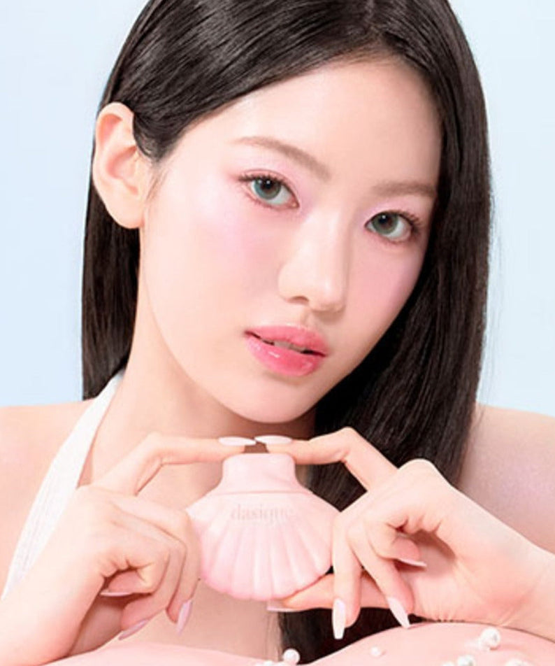 Model holding DASIQUE Glow Shell Base with soft pink makeup, showcasing the product's elegant shell design.
