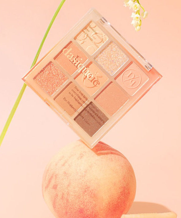 DASIQUE Shadow Palette #14 Peach Squeeze displayed on a peach background with floral accents, featuring shimmering peach tones.