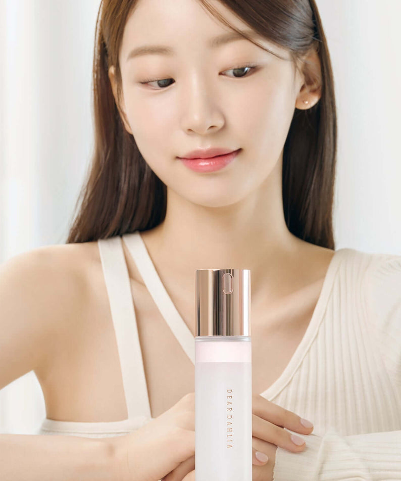 Woman holding DEAR DAHLIA Endless Skin Cream Mist in elegant packaging.
