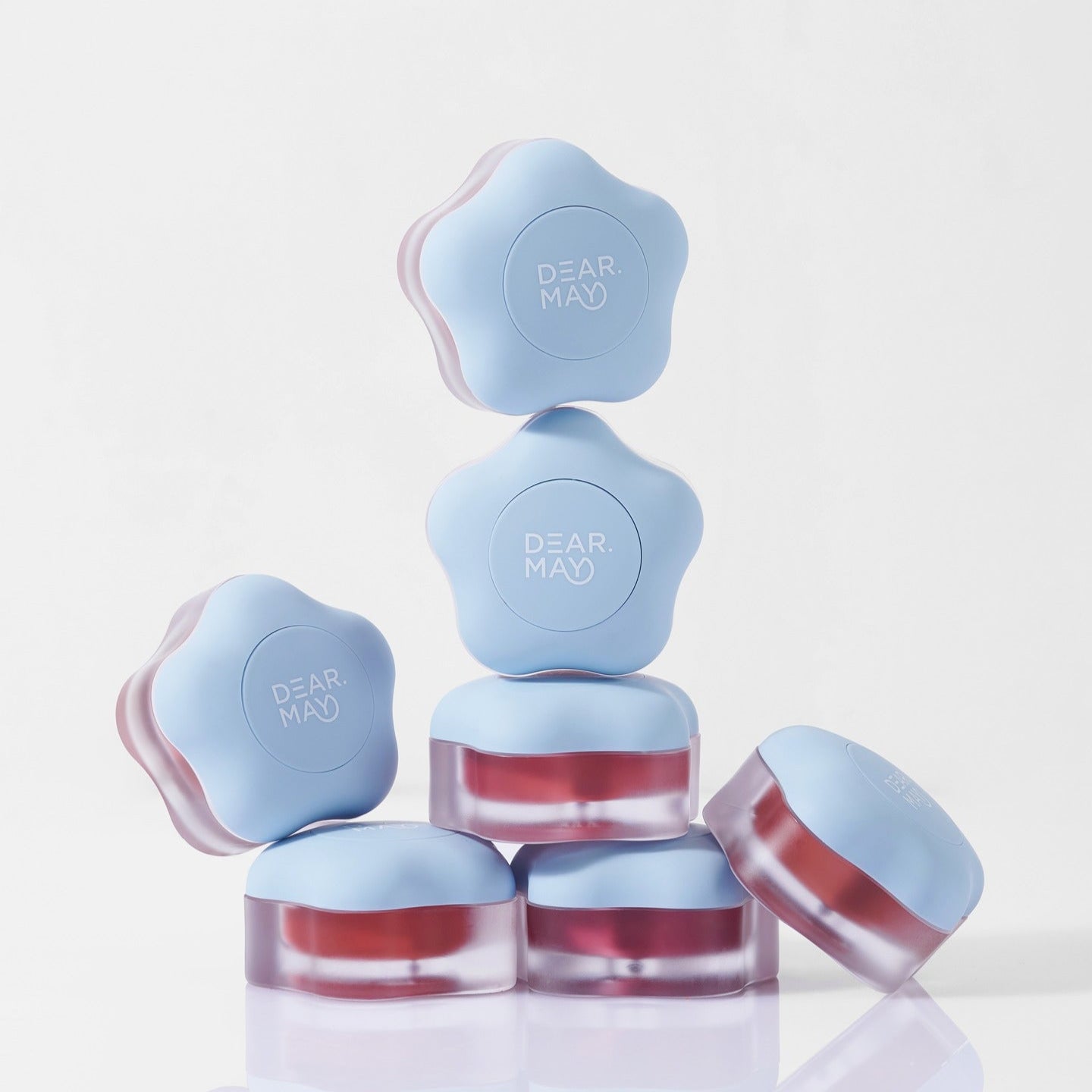 Stack of DEAR MAY Pure Falling Mood Lip Pot 6.5g containers with blue lids and product name visible, designed for mood enhancement.