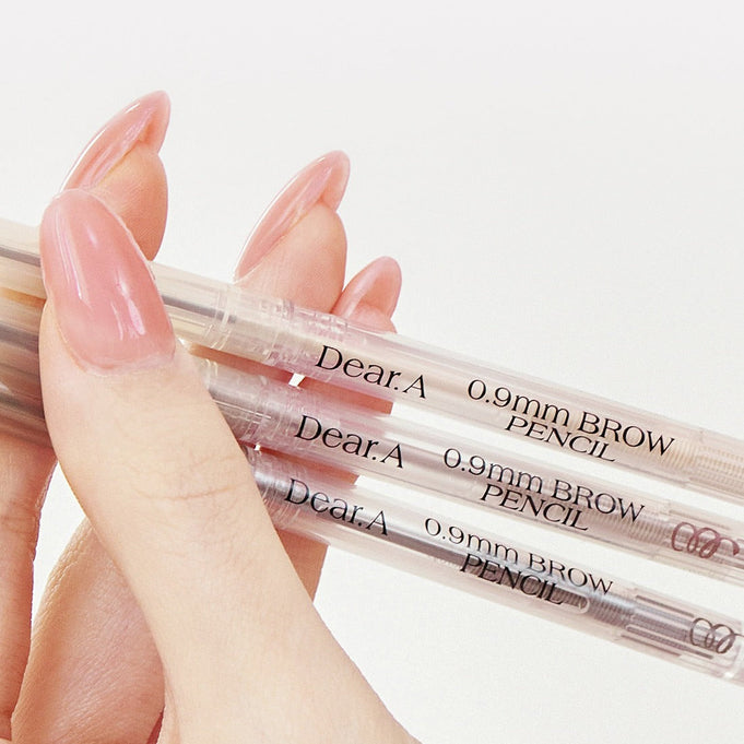 Close-up of hand holding DEAR.A 0.9mm Eyebrow pencils with clear packaging and text.
