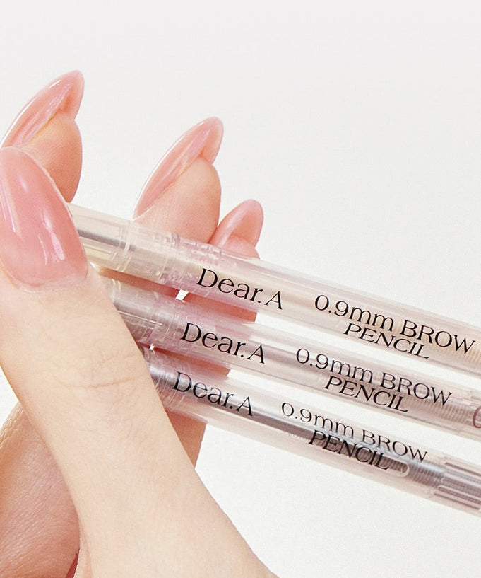 Close-up of hand holding DEAR.A 0.9mm Eyebrow pencils with clear packaging and text.