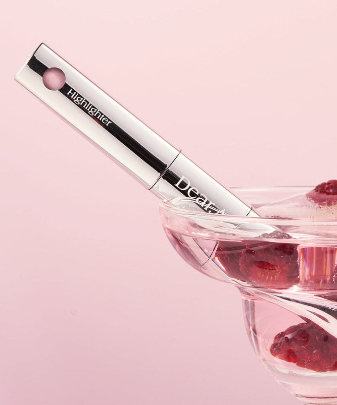 DEAR.A Blush & Beam Dual Stick with berries in a glass bowl, showcasing its sleek design against a pink background.