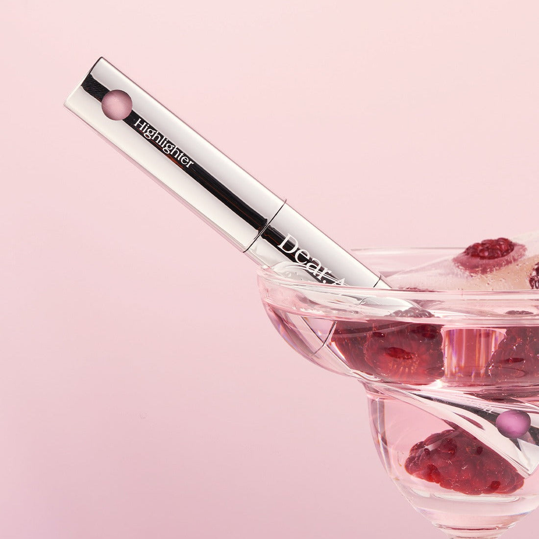 DEAR.A Blush & Beam Dual Stick with berries in a glass bowl, showcasing its sleek design against a pink background.