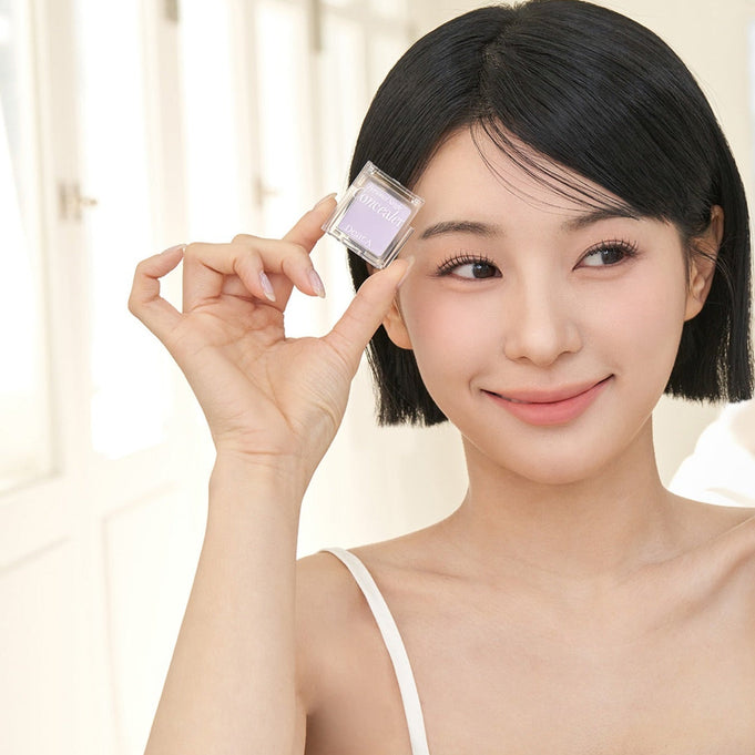 Woman holding DEAR.A Single Concealer 10 Colors smiling indoors
