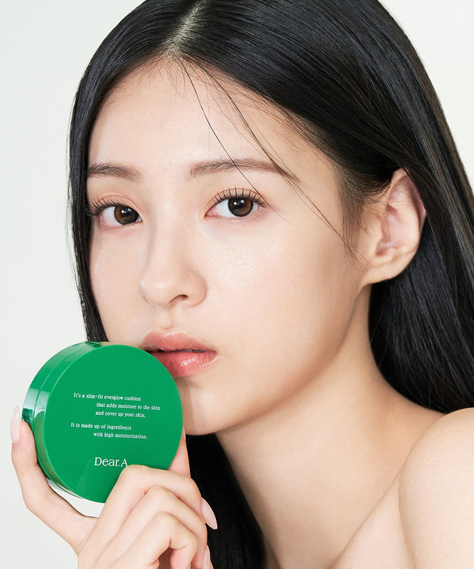 Model holding DEAR.A Slim Fit Everglow Cushion 10g showcasing the product's packaging and use on smooth skin.