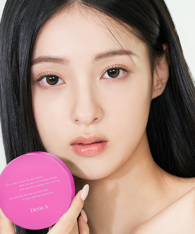 Model holding DEAR.A Slim Fit Tone-Up Sun Cushion 30ml, showcasing lightweight and protective skincare in vibrant packaging.