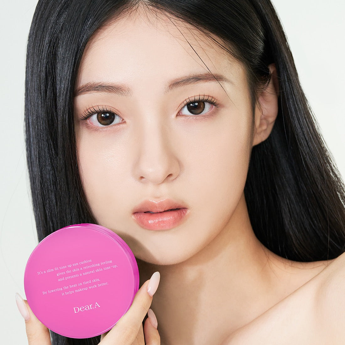 Model holding DEAR.A Slim Fit Tone-Up Sun Cushion 30ml, showcasing lightweight and protective skincare in vibrant packaging.