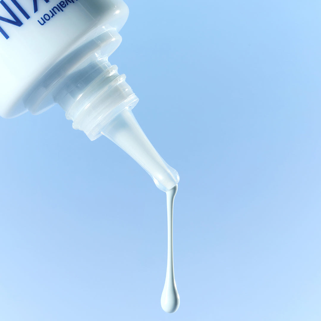Close-up of DERMATORY Hyaluronic Skin Prep Sun Cream B5 52ml with drop against blue background