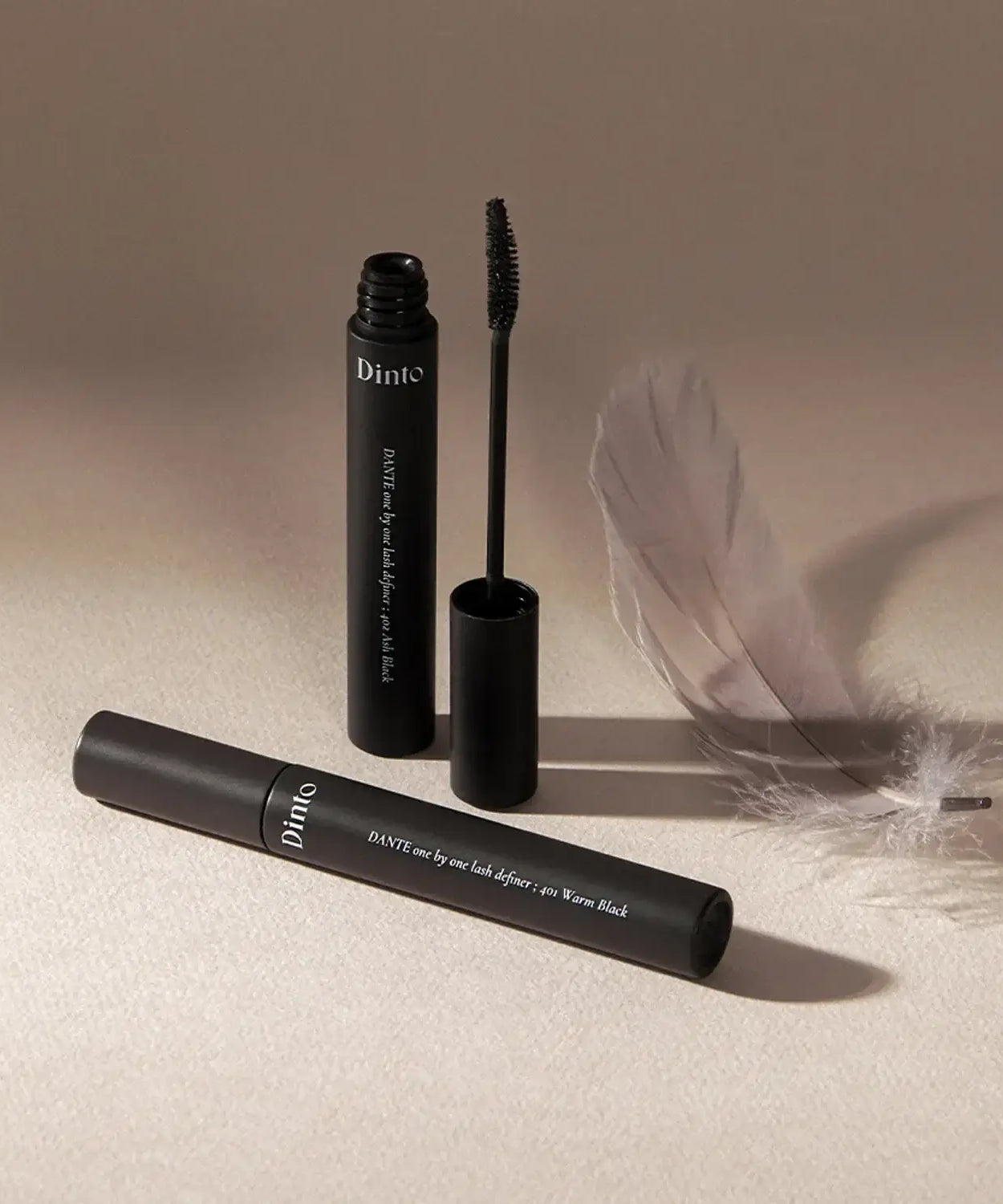 DINTO Dante Lash Definer mascara with open brush and feather, showcasing elegance and style.