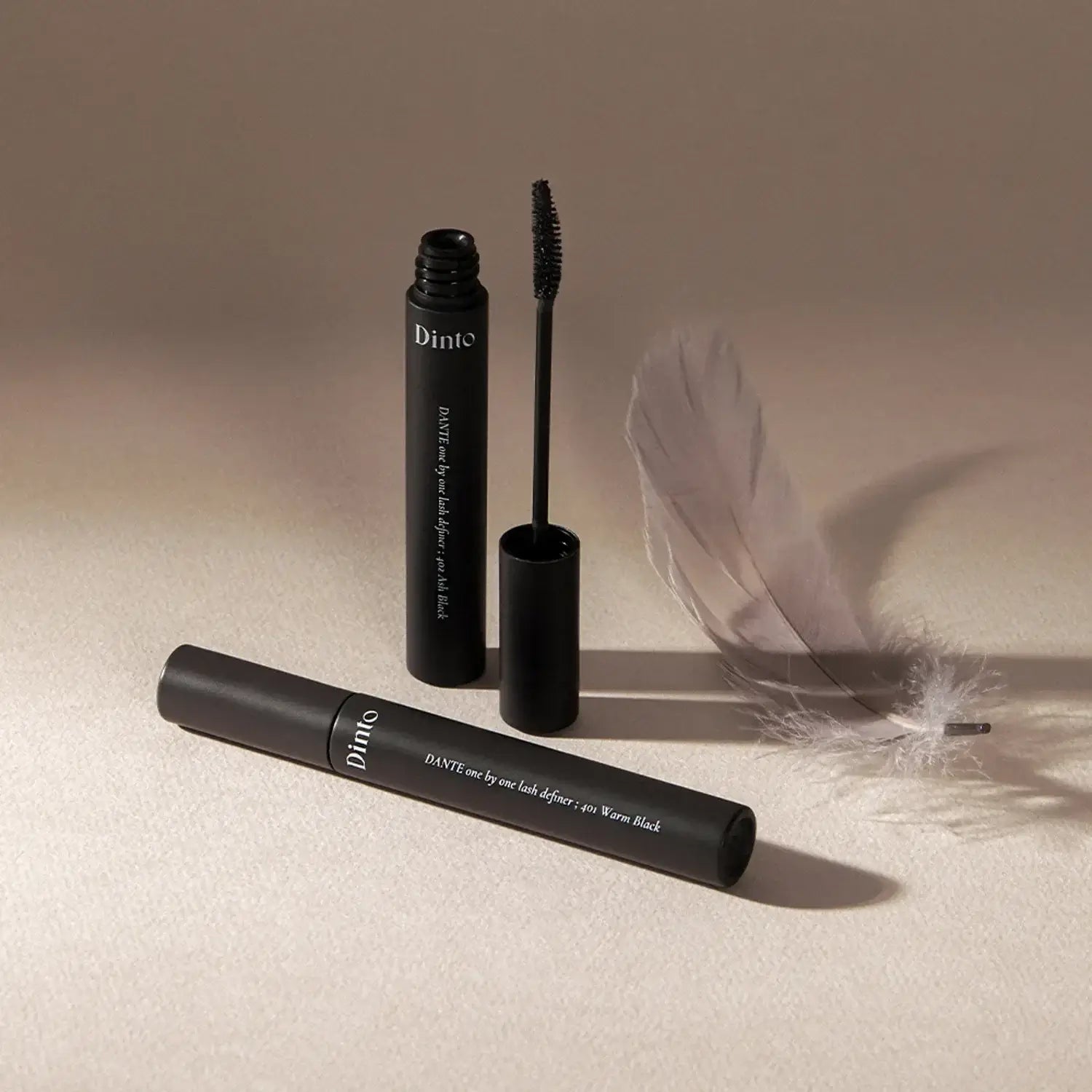 DINTO Dante Lash Definer mascara with open brush and feather, showcasing elegance and style.