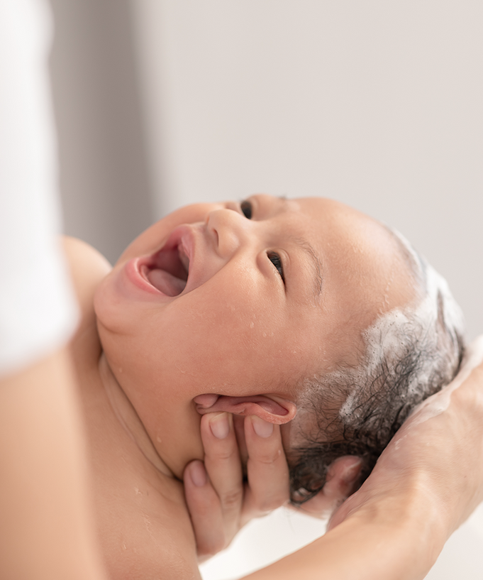 Baby smiling during bath with DONGGUBAT Correct Baby Soap Aloe, gentle hair wash, parent hands support.