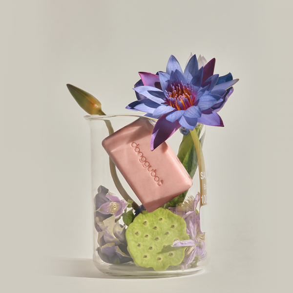 DONGGUBAT Blooming Jaungo Washing Bar 80g in a beaker with flowers and green lotus seed pod