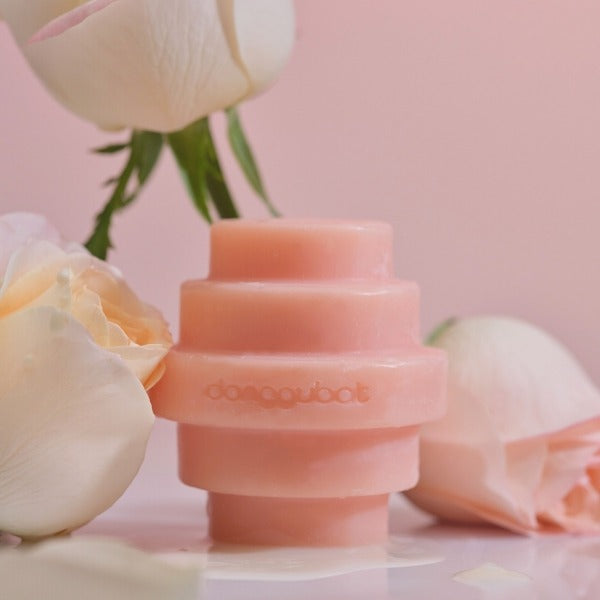 DONGGUBAT Eau De Toilette Object Perfume Bar Mellow Rosa Garden 150g surrounded by flowers on a soft pink background.